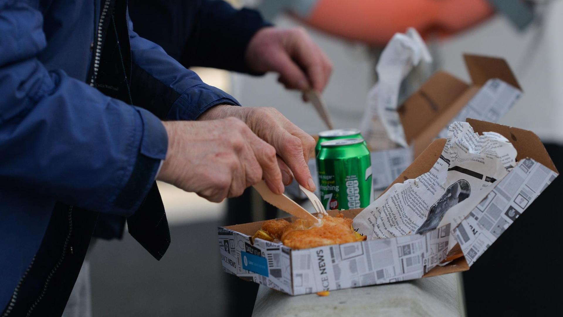 Kunden genießen ein traditionelles Fish and Chips-Gericht. Kunden genießen ein traditionelles Fish and Chips-Gericht.