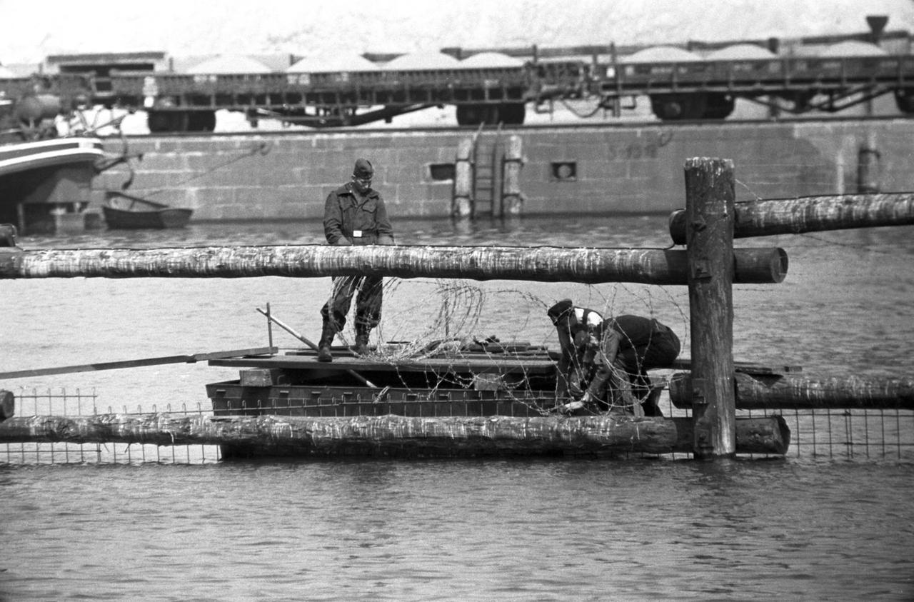Drahthindernisse werden 1963 über und unter der Wasseroberfläche der Spree befestigt. Drahthindernisse werden 1963 über und unter der Wasseroberfläche der Spree befestigt.