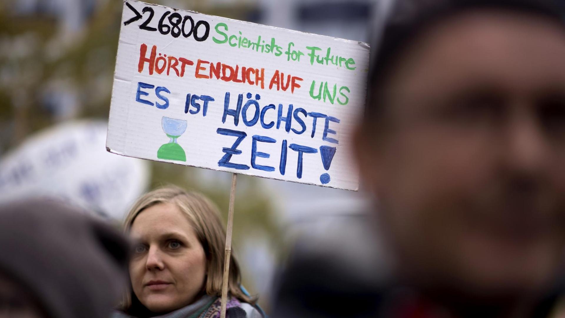 Eine Demonstrantin hält ein Schild hoch, auf dem steht: "26800 Scientists for Future: Hört endlich auf uns! Es ist höchste Zeit"