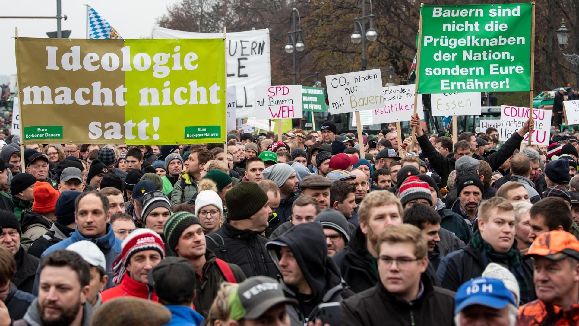 Viele Bauern stehen bei einer Protestaktion gegen das Agrarpaket der Bundesregierung auf der Straße des 17. Juni vor dem Brandenburger Tor und halten Plakate mit der Aufschrift "Ideologie macht nicht satt" und "Bauern sind nicht die Prügelknaben der Nation, sondern Eure Ernährer!". Viele Bauern stehen bei einer Protestaktion gegen das Agrarpaket der Bundesregierung auf der Straße des 17. Juni vor dem Brandenburger Tor und halten Plakate mit der Aufschrift "Ideologie macht nicht satt" und "Bauern sind nicht die Prügelknaben der Nation, sondern Eure Ernährer!".
