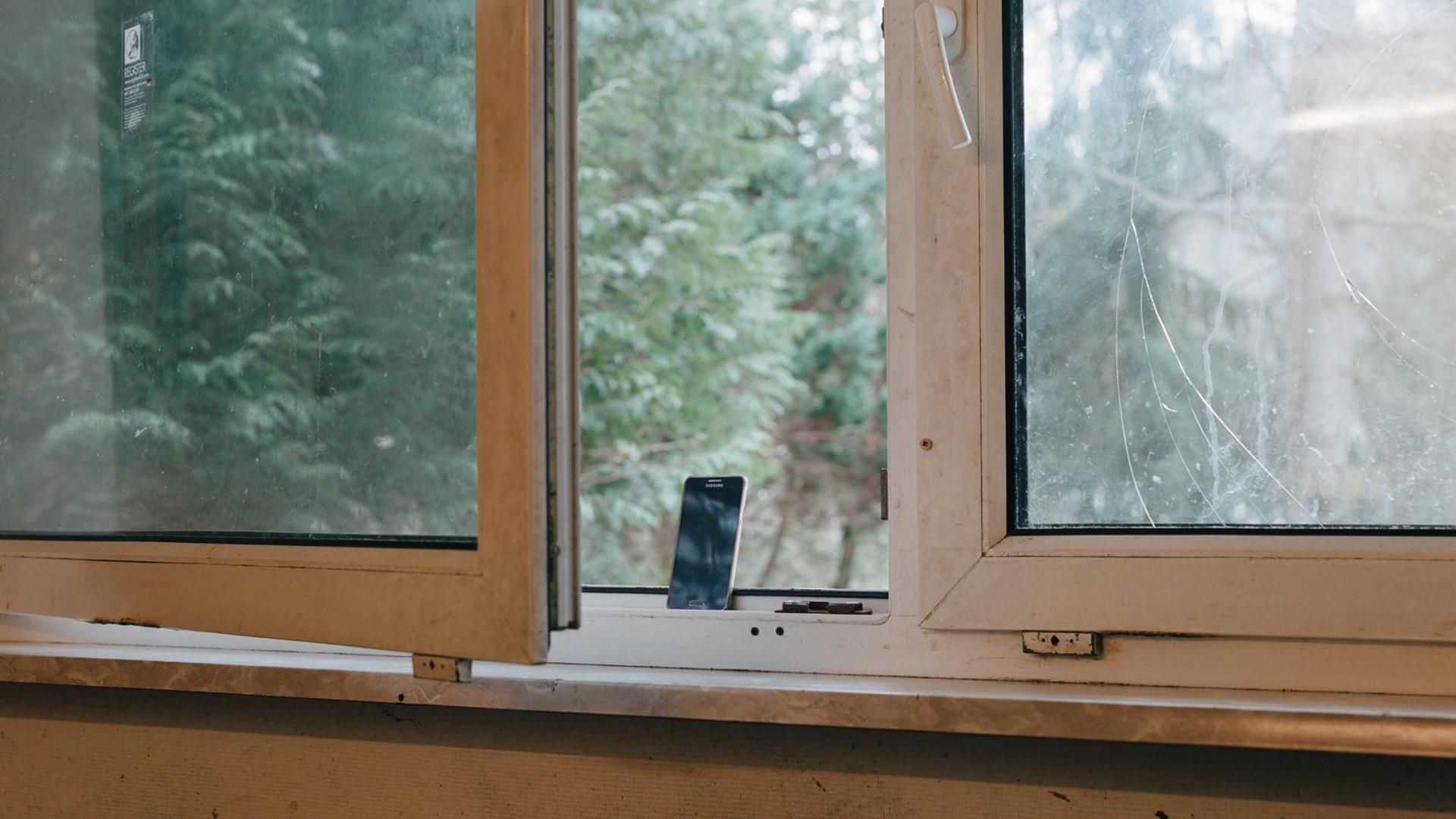 Foto von einem Handy am Fenster aus der Serie „Holzbachtal, nothing, nothing“ von Sibylle Fendt