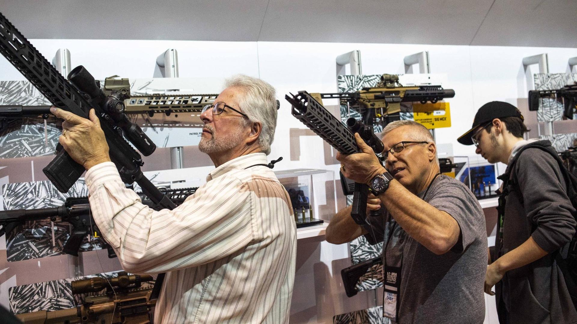 Besucher der NRA-Jahresversammlung begutachten Waffen.