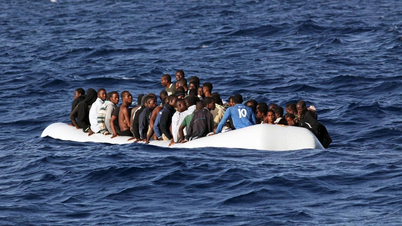 Ein mit Menschen überfülltes Schlauchboot treibt auf dem Mittelmeer. Ein mit Menschen überfülltes Schlauchboot treibt auf dem Mittelmeer.
