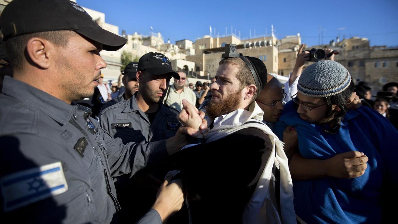 Ein ultra-orthodoxer jüdischer Mann streitet mit einem Polizeibeamten, während eines von der Organisation "Women of the Wall" organisierten Gebetes, das nicht abgebildet ist.
Ein ultra-orthodoxer jüdischer Mann streitet mit einem Polizeibeamten, während eines von der Organisation "Women of the Wall" organisierten Gebetes, das nicht abgebildet ist.