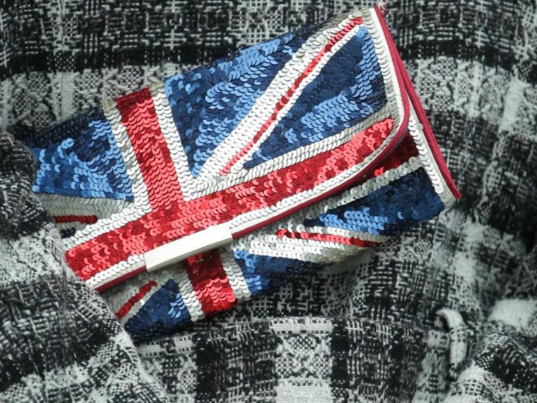 Eine Frau mit einer Handtasche (Clutch) in britischen Farben steht während des Besuchs von Königin Elizabeth II am Spreeufer in Berlin.