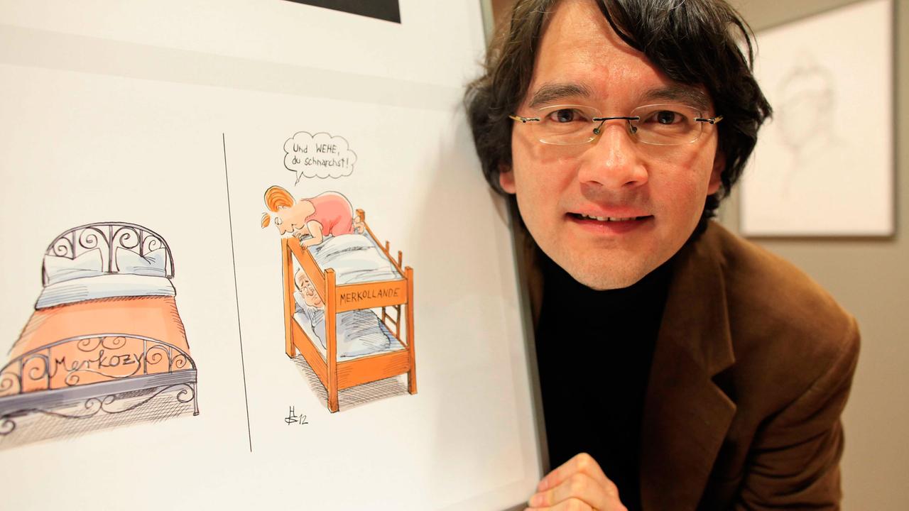 Der deutsche Karikaturist Heiko Sakurai zeigt sein Werk zum "Europäischen Paar" Deutschland und Frankreich bei einer Ausstellungseröffnung. Der deutsche Karikaturist Heiko Sakurai zeigt sein Werk zum "Europäischen Paar" Deutschland und Frankreich bei einer Ausstellungseröffnung.