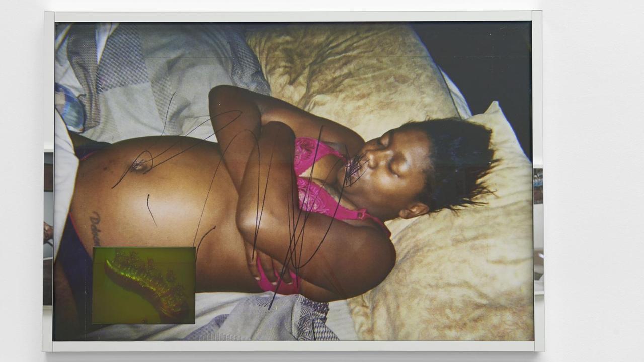 Das Bild zeigt die Fotografie einer Afroamerikanerin, die halb nackt im Bett liegt. Das Bild zeigt die Fotografie einer Afroamerikanerin, die halb nackt im Bett liegt.