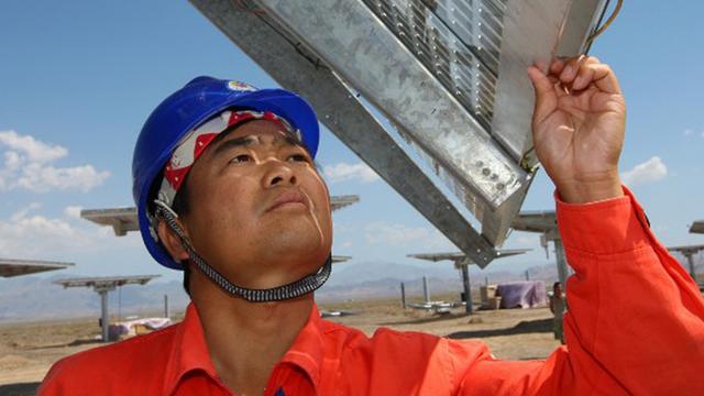 Ein Arbeiter prüft ein Solarpanel auf einem Feld im chinesischen Hami.
