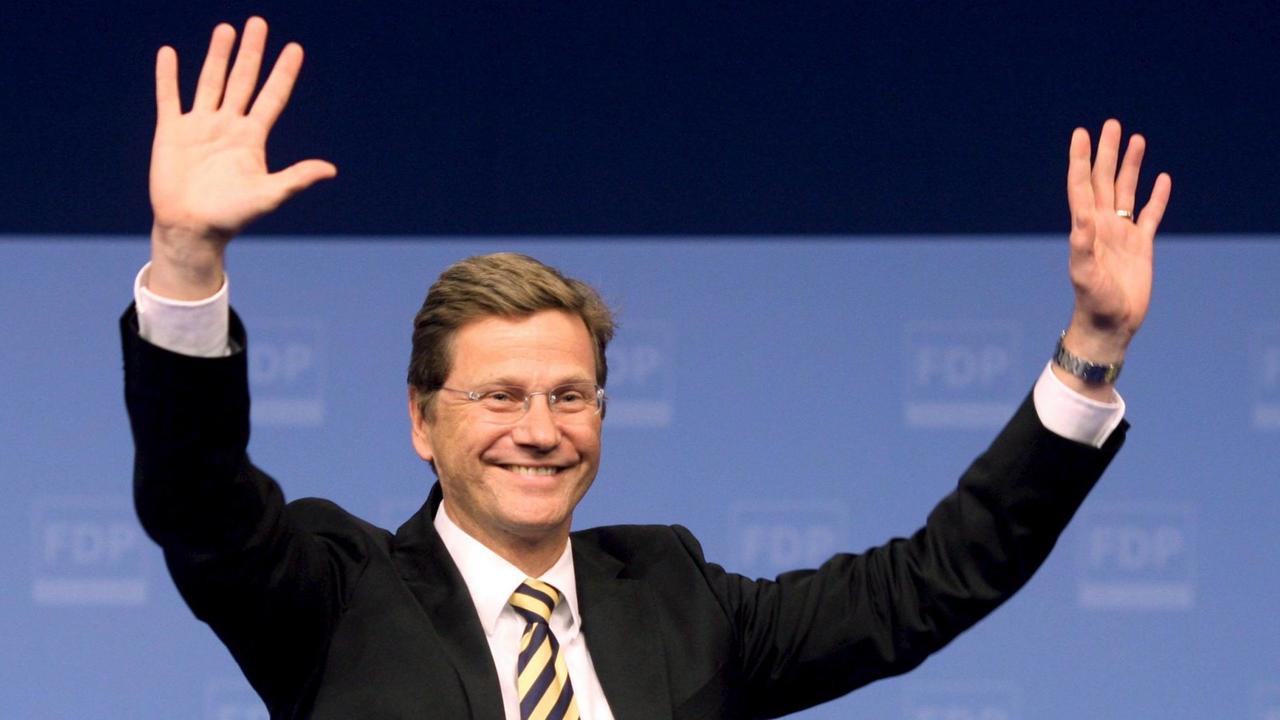 Guido Westerwelle (FDP), lächelt mit erhobenen Armen. 