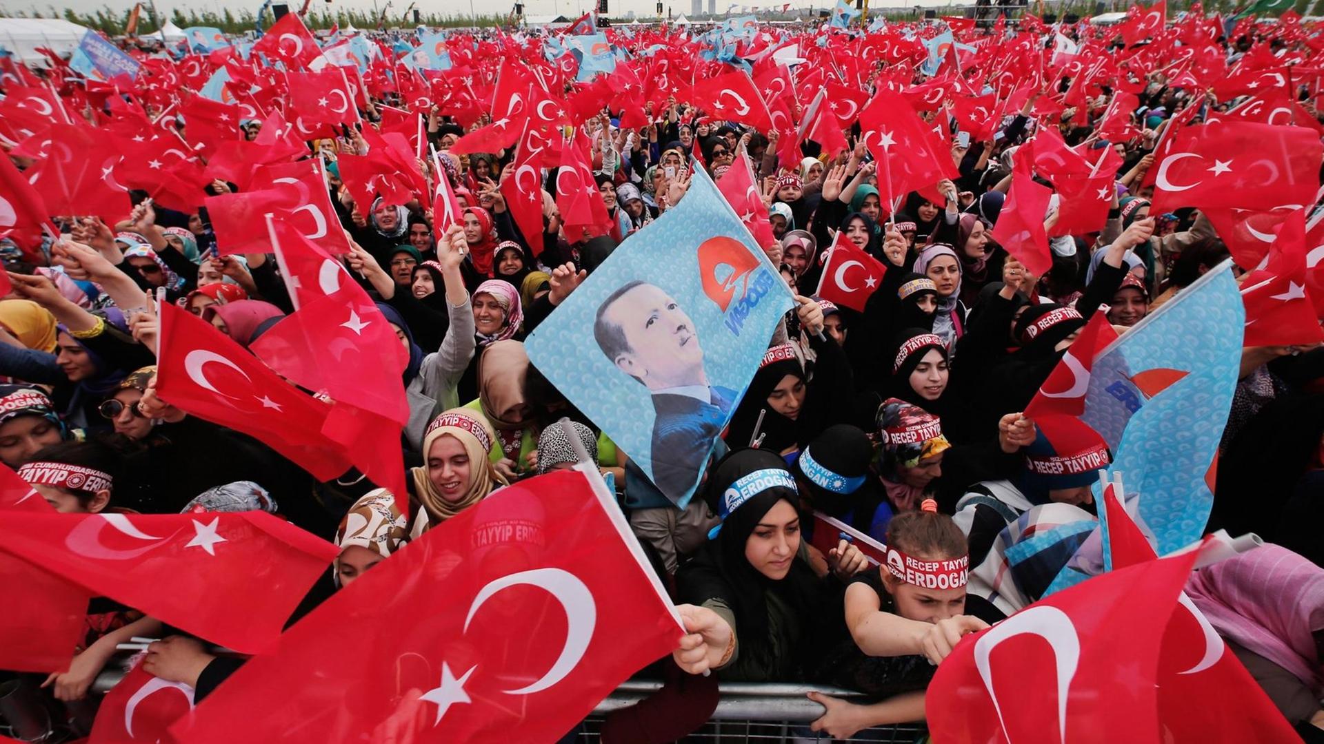 Unterstützer der regierenden AKP schwenken die Flagge der Türkei und halten ein Bild Erdogans hoch. Unterstützer der regierenden AKP schwenken die Flagge der Türkei und halten ein Bild Erdogans hoch.