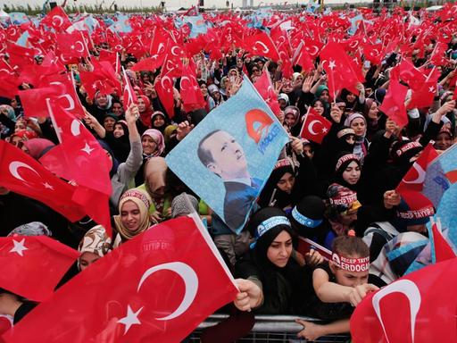 Unterstützer der regierenden AKP schwenken die Flagge der Türkei und halten ein Bild Erdogans hoch.