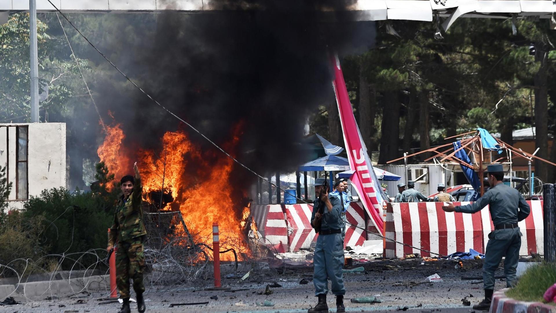 Afghanische Sicherheitskräfte vor brennenden Trümmern nach der Explosion am Kabuler Flughafen.