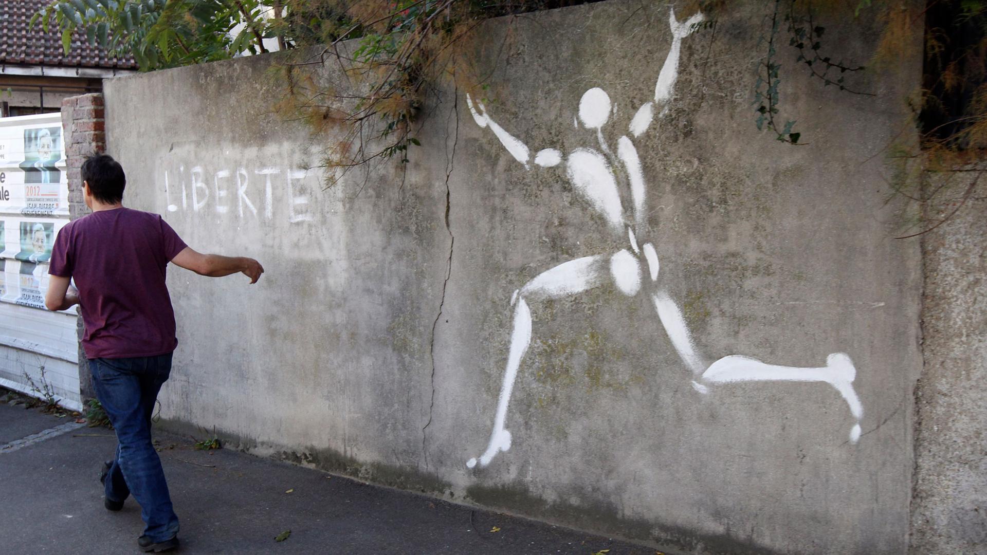 Der französische Künstler Jerome Mesnager geht an einem seiner Kunstwerke, dem "Mann in Weiß", in Montreuil-sous-Bois vorbei. Der französische Künstler Jerome Mesnager geht an einem seiner Kunstwerke, dem "Mann in Weiß", in Montreuil-sous-Bois vorbei.