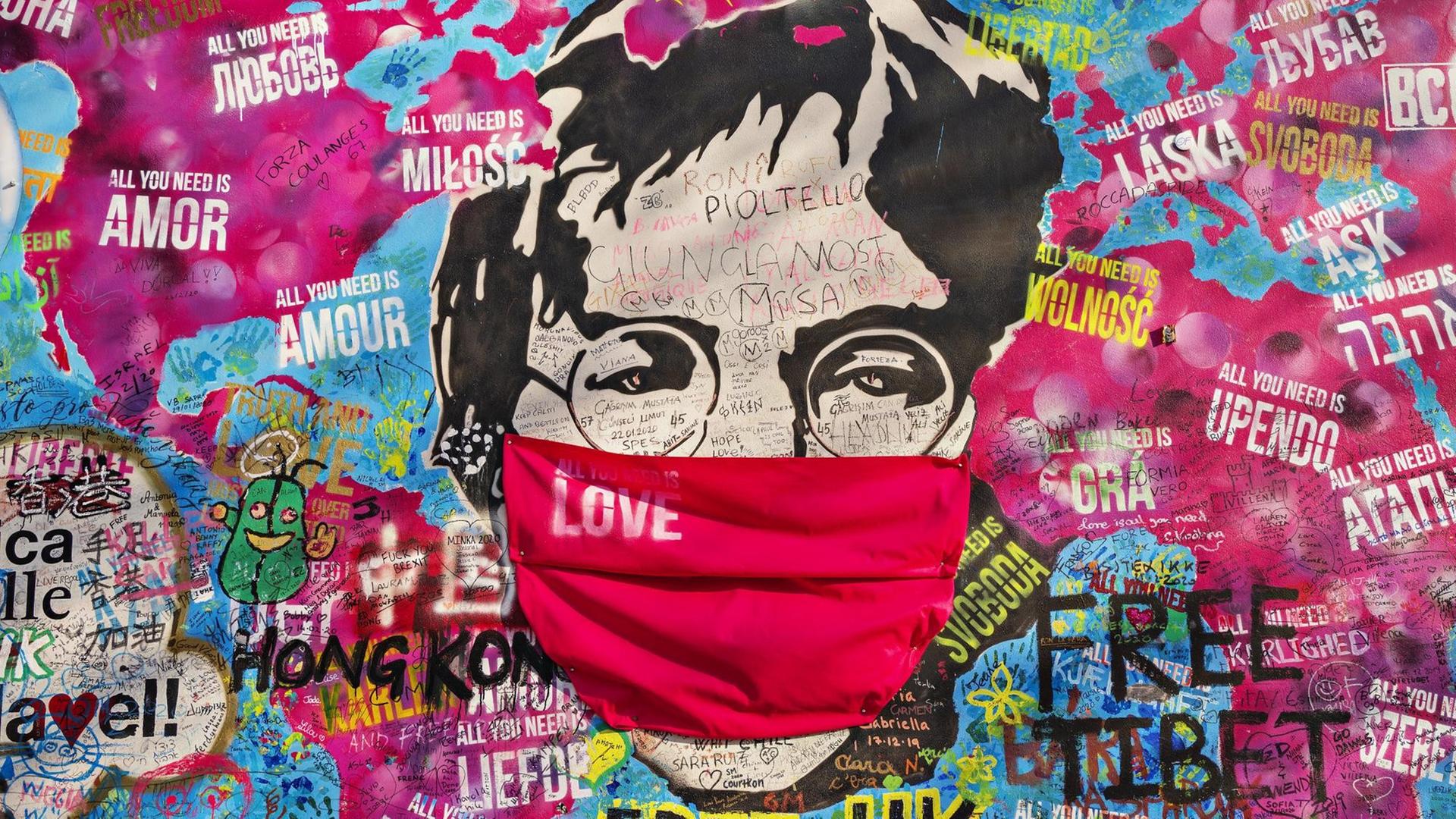 John Lennon-Graffito mit Atemschutz auf einer Weltkarte mit "All you need is love"-Sprüchen John Lennon-Graffito mit Atemschutz auf einer Weltkarte mit "All you need is love"-Sprüchen