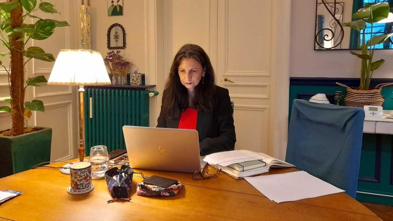 Eine Frau mit langen, dunklen Haaren sitzt über ein Laptop gebeugt an einem großen Tisch aus hellem Holz. Eine Frau mit langen, dunklen Haaren sitzt über ein Laptop gebeugt an einem großen Tisch aus hellem Holz.