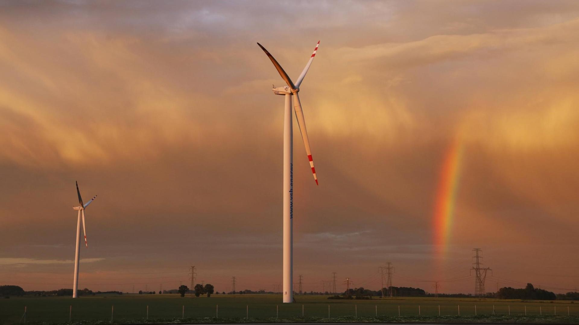 Windränder vor dramatischem Himmel mit Regenbogen entlang einer Autobahn Windränder vor dramatischem Himmel mit Regenbogen entlang einer Autobahn