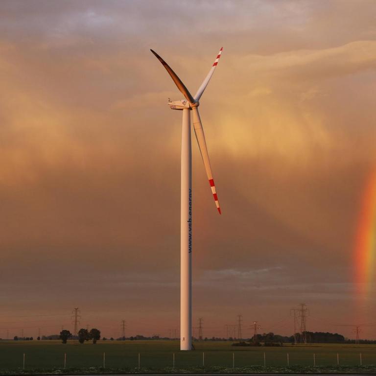 Windränder vor dramatischem Himmel mit Regenbogen entlang einer Autobahn