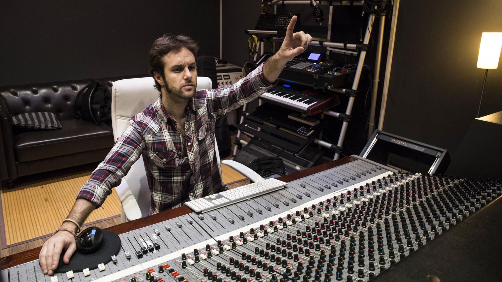 Ein Mann sitzt am Mischpult eines Musikstudios. Ein Mann sitzt am Mischpult eines Musikstudios.