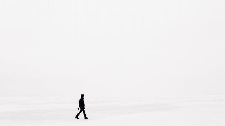 Eine Person läuft in weißem Nebel über Schnee Eine Person läuft in weißem Nebel über Schnee