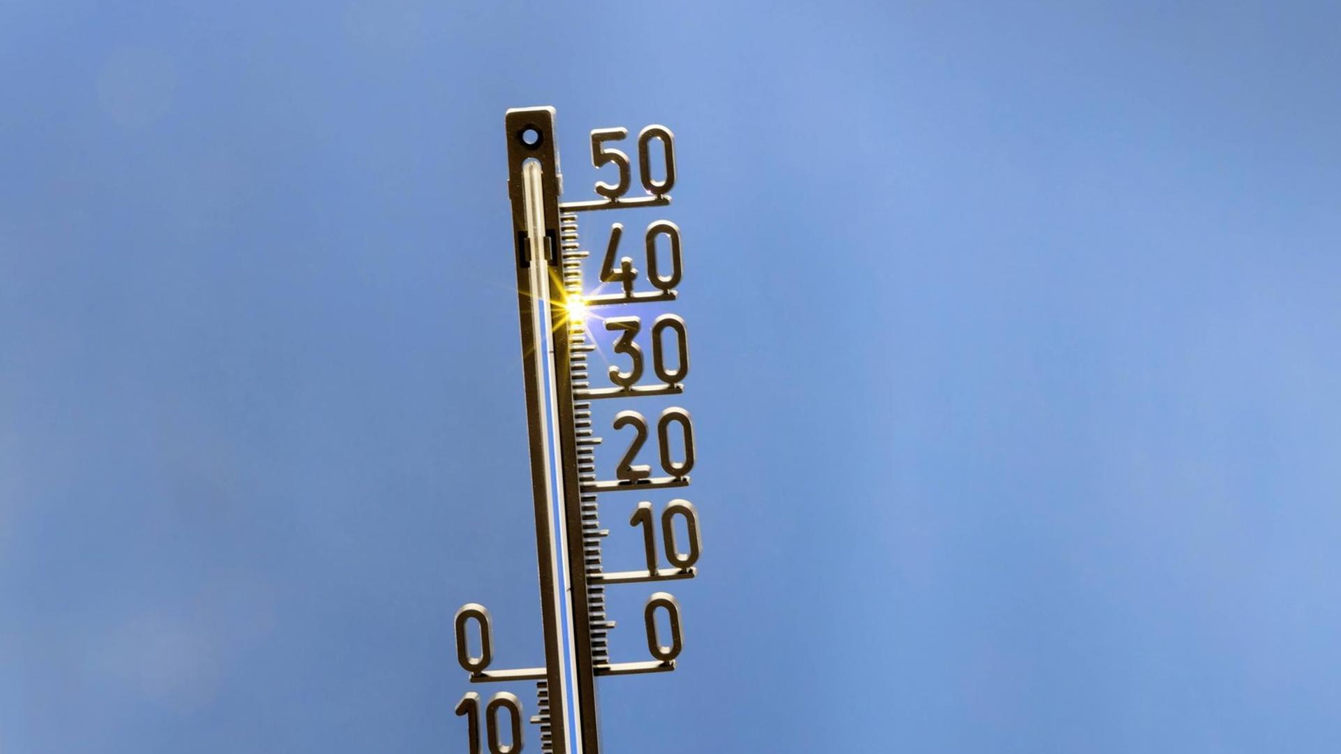 Ein analoges Thermometer vor blauem Himmel zeigt 40 Grad Celsius an.