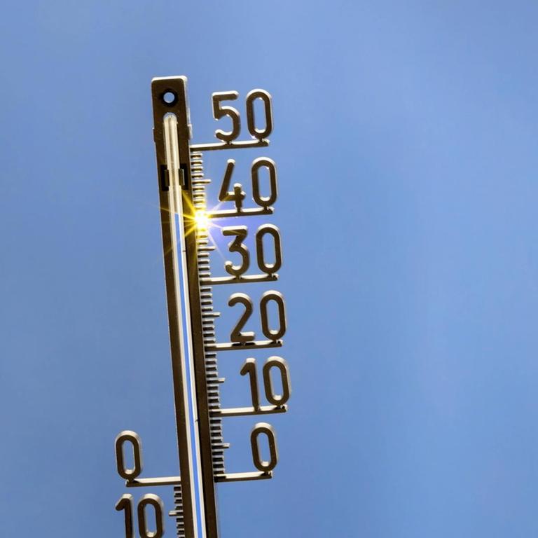 Ein analoges Thermometer vor blauem Himmel zeigt 40 Grad Celsius an.
