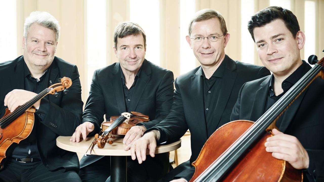 Das Aperto Piano Quartett sitzt an einem kleinen Tisch beieinander: Frank Reinecke (Violine), Stefan Fehlandt (Viola), Jonathan Weigle (Violoncello), Frank-Immo Zichner (Klavier). Das Aperto Piano Quartett sitzt an einem kleinen Tisch beieinander: Frank Reinecke (Violine), Stefan Fehlandt (Viola), Jonathan Weigle (Violoncello), Frank-Immo Zichner (Klavier).