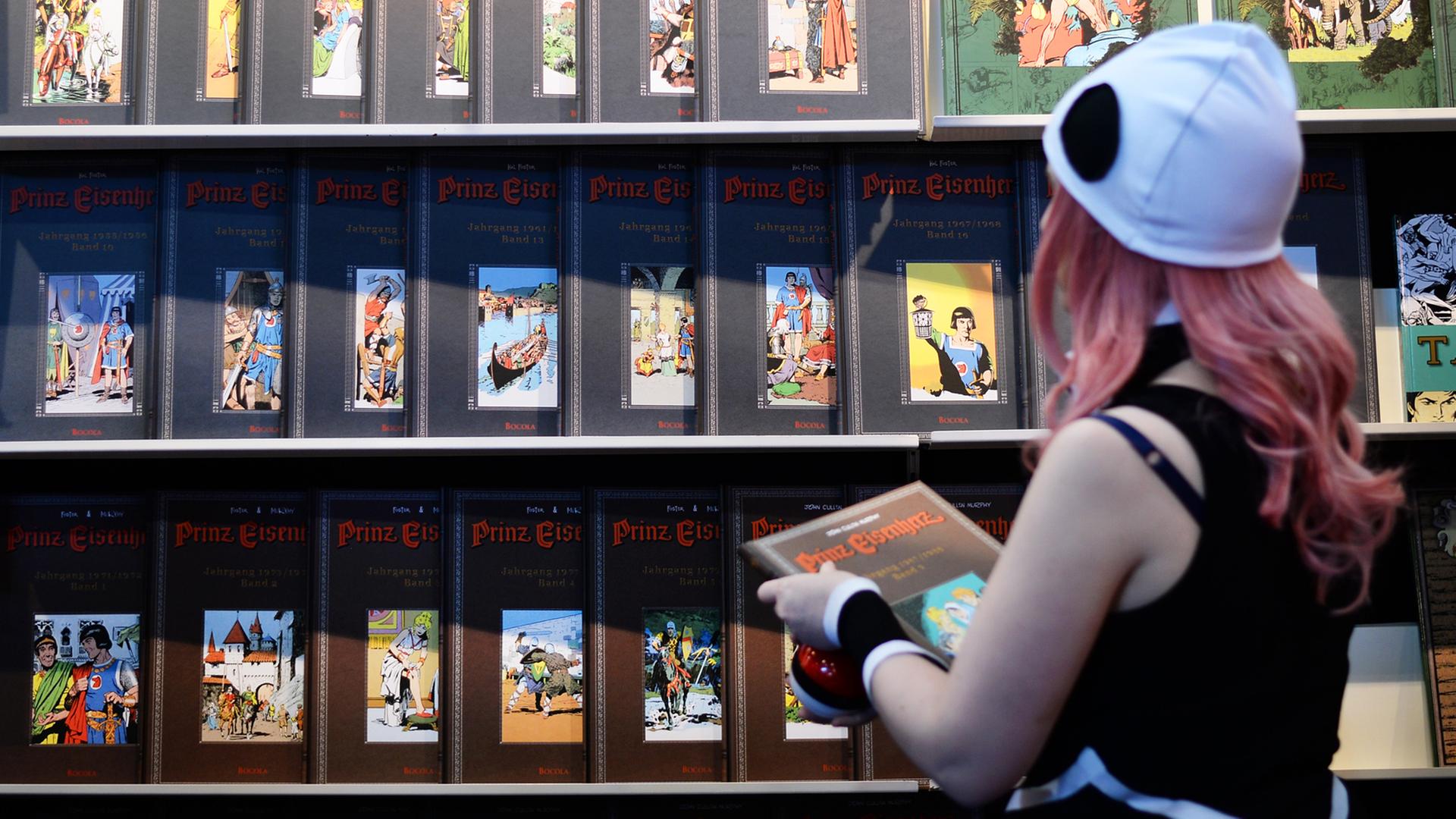 Eine Cosplayerin schaut sich 2017 auf der Buchmesse in Leipzig an einem Stand neue Comics und Bücher an. Eine Cosplayerin schaut sich 2017 auf der Buchmesse in Leipzig an einem Stand neue Comics und Bücher an.
