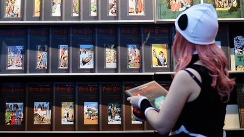 Eine Cosplayerin schaut sich 2017 auf der Buchmesse in Leipzig an einem Stand neue Comics und Bücher an.