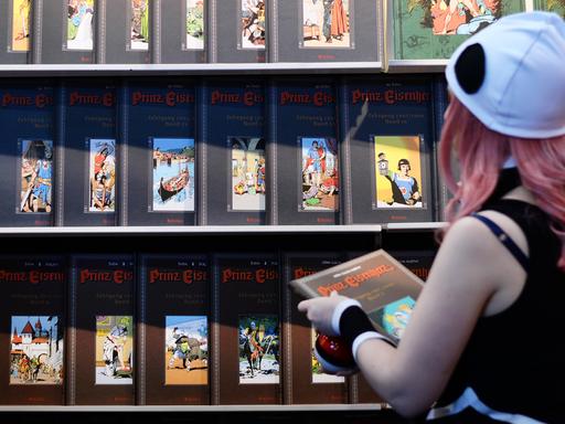 Eine Cosplayerin schaut sich 2017 auf der Buchmesse in Leipzig an einem Stand neue Comics und Bücher an.