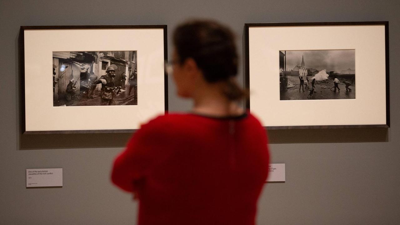 Eine Besucherin schaut sich zwei schwarz-weiß Fotos an der Wand an. Eine Besucherin schaut sich zwei schwarz-weiß Fotos an der Wand an.