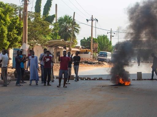 Auf einer Straße in der sudanesischen Hauptstadt Khartoum demonstrieren Menschen neben einem brennenden Autoreifen. 