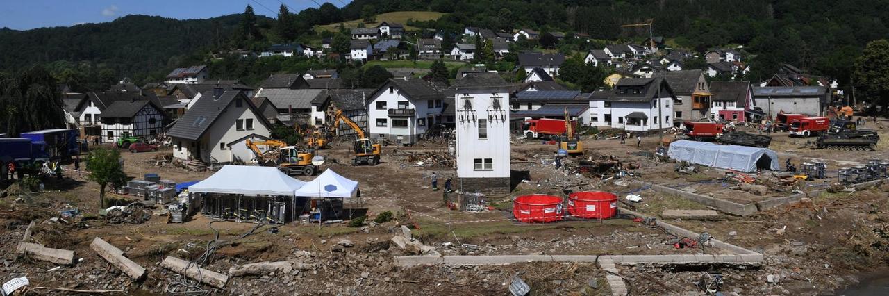 Einzelne Gebäude stehen auf schlammigem Brachland, dazwischen Zelte der Rettungskräfte Einzelne Gebäude stehen auf schlammigem Brachland, dazwischen Zelte der Rettungskräfte