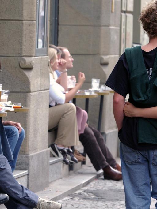 Ein junges Paar flaniert in Berlin-Mitte an einem Café vorbei.
