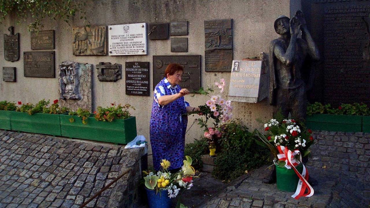 Eine Frau wechselt Blumen am Denkmal des ermordeten Priesters Jerzy Popieluszko vor der ehemaligen Lenin-Werft in Gdansk. Eine Frau wechselt Blumen am Denkmal des ermordeten Priesters Jerzy Popieluszko vor der ehemaligen Lenin-Werft in Gdansk.