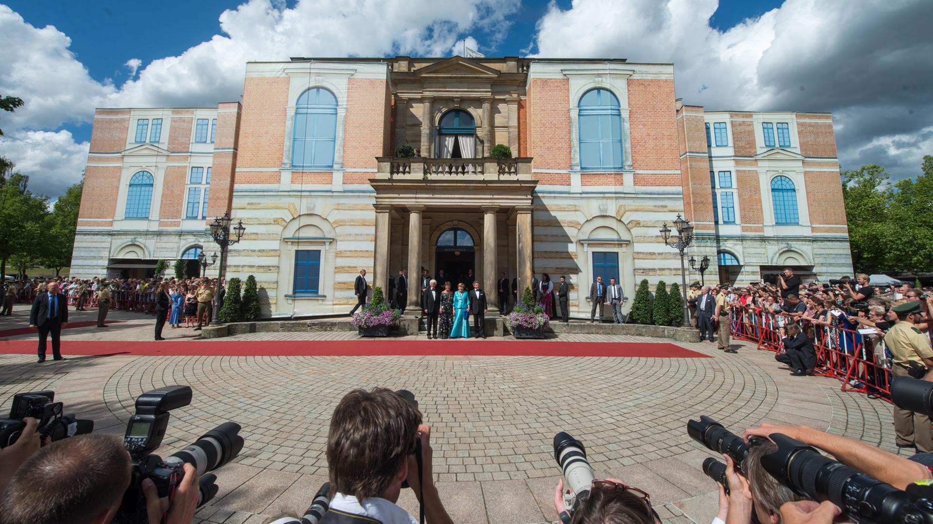 Zu sehen ist das Festspielhaus in Bayreuth, davor steht in türkis Bundeskanzlerin Merkel. Zu sehen ist das Festspielhaus in Bayreuth, davor steht in türkis Bundeskanzlerin Merkel.