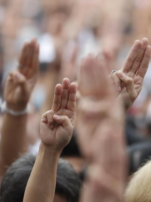Proteste in Bangkok, Thailand. Die Menschen halten die Hände mit dem Drei-Finger-Gruß in die Luft, 15.10.2020