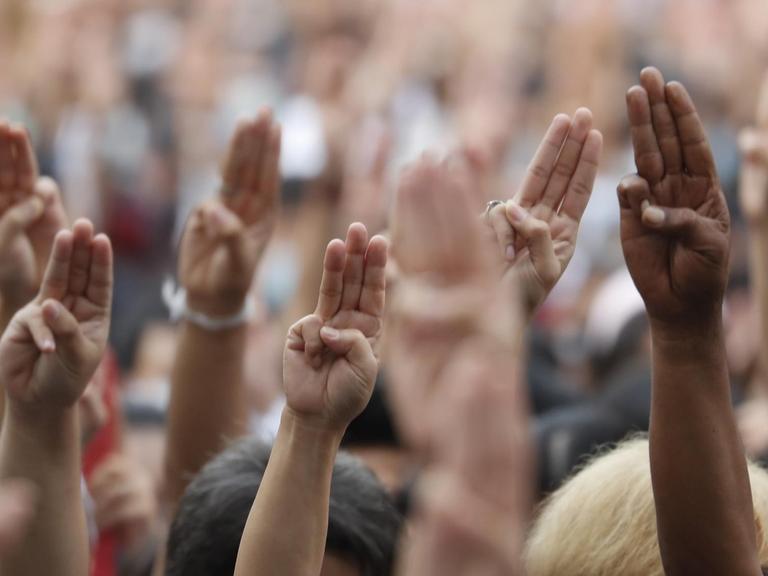 Proteste in Bangkok, Thailand. Die Menschen halten die Hände mit dem Drei-Finger-Gruß in die Luft, 15.10.2020