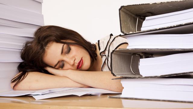 Eine junge Beschäftigte schläft am Arbeitsplatz ein.