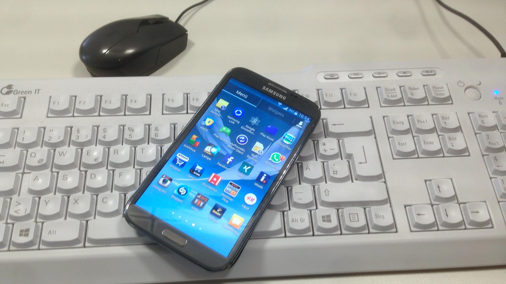 Ein Smartphone liegt auf einer PC-Tastatur Ein Smartphone liegt auf einer PC-Tastatur