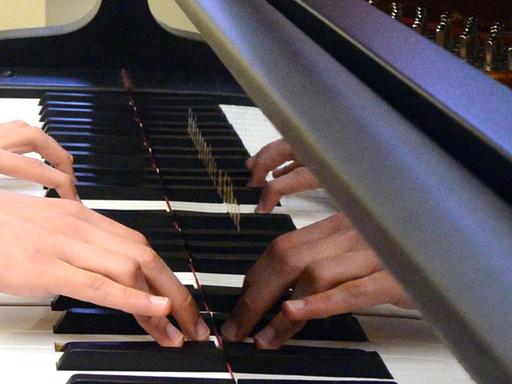 Hände spielen auf einem Klavier.