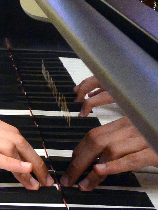 Hände spielen auf einem Klavier.