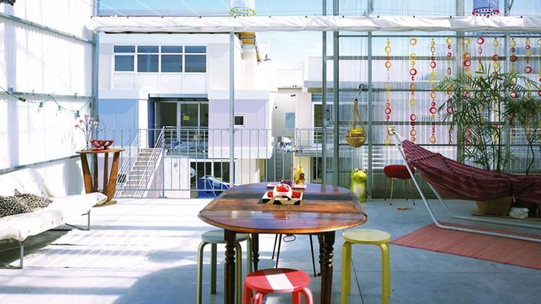 Sozialer Wohnungsbau des Architekturbüros Lacaton & Vassal, ein offener Bereich mit Tisch, Hängematte und Sofa.