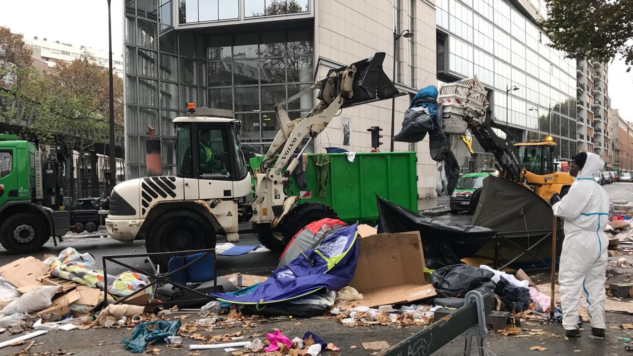 Ein Bagger, der über zerstörte Zelte fährt. Ein Bagger, der über zerstörte Zelte fährt.