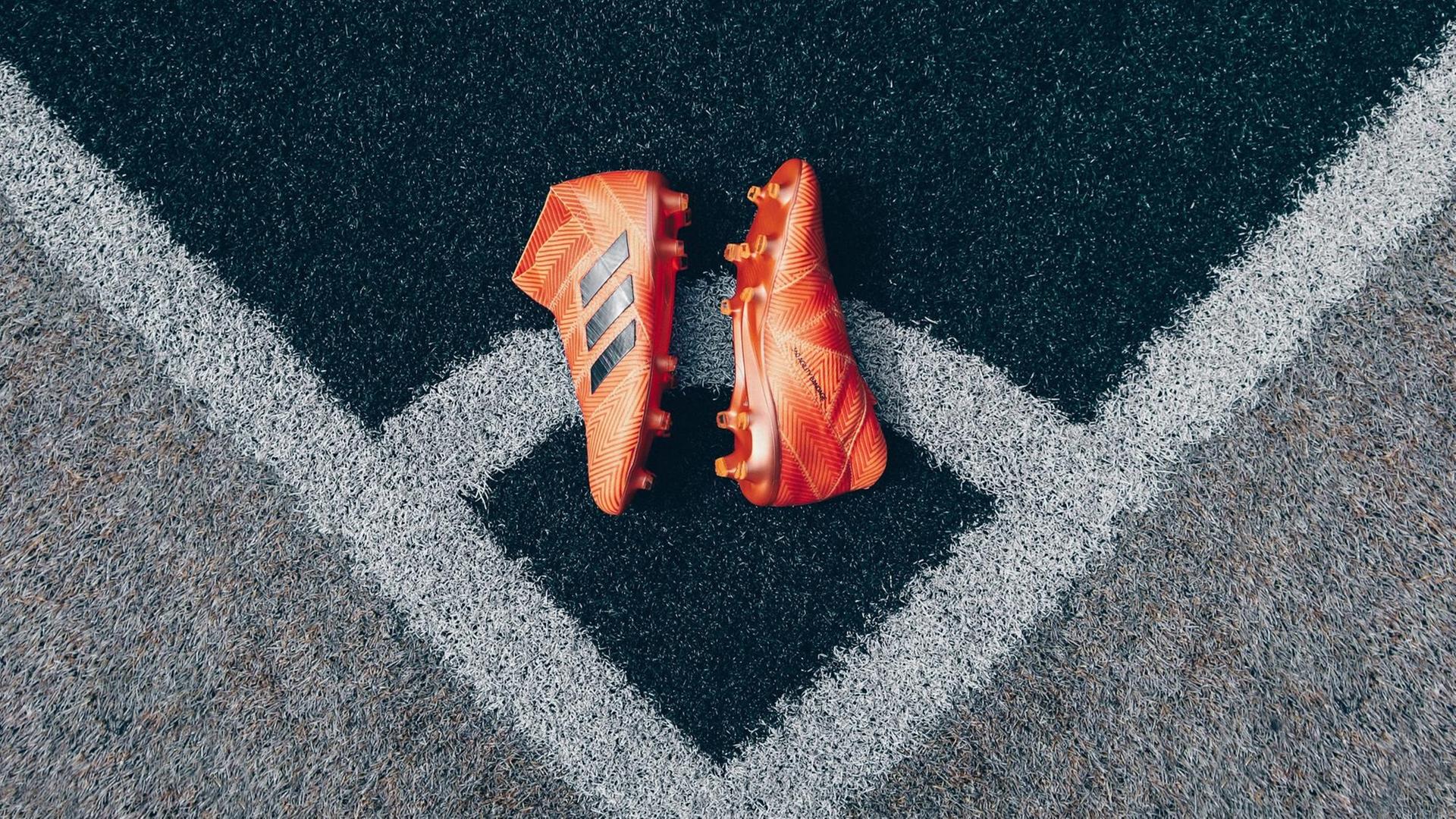 Ein paar Sportschuhe in orange liegt auf einem garuen Kunstrasen. Ein paar Sportschuhe in orange liegt auf einem garuen Kunstrasen.