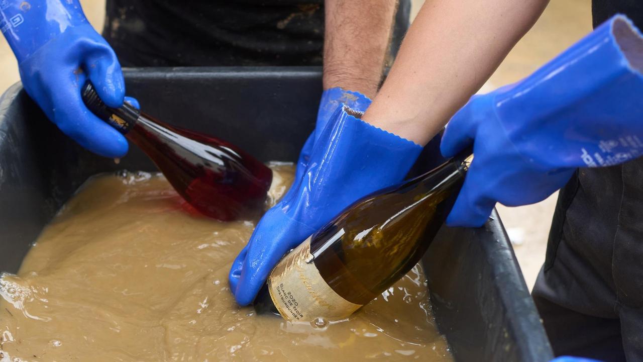 Freiwillige Helfer sind am Weingut Adeneuer damit beschäftigt, die durch die Flut mit Schlamm bedeckten Flaschen zu reinigen. Im durch das Hochwasser stark verwüsteten Ahrtal gehen die Aufräumarbeiten unvermindert weiter.