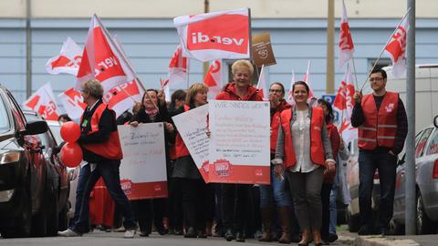 Erzieherinnen und Erzieher demonstrieren am 09.04.2015 in Magdeburg für mehr Geld, dabei halten sie mehrere Plakate und Verdi-Fahnen hoch.