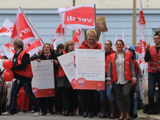 Erzieherinnen und Erzieher demonstrieren am 09.04.2015 in Magdeburg für mehr Geld, dabei halten sie mehrere Plakate und Verdi-Fahnen hoch.