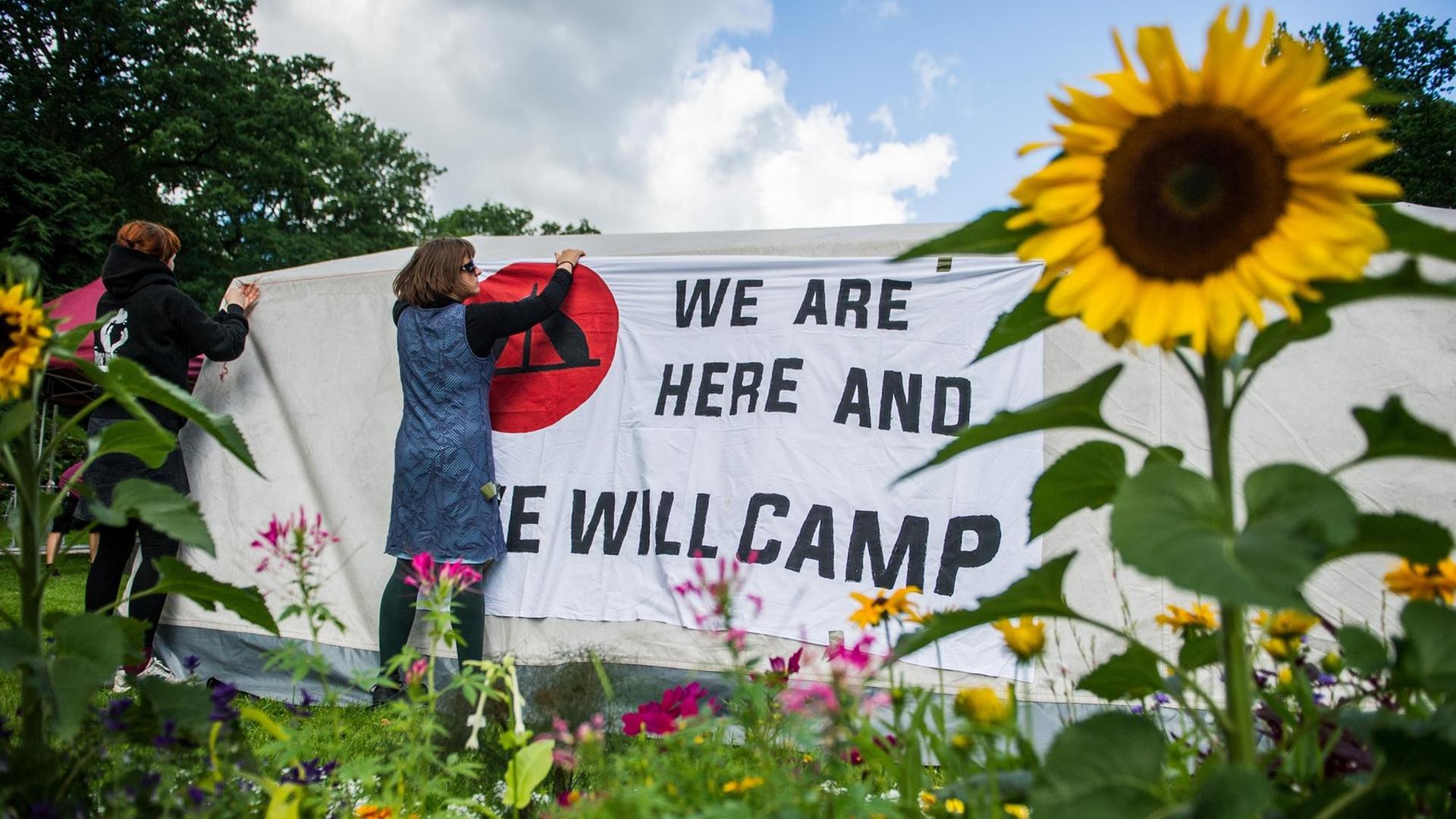 Unterstützer des Antikapitalistischen Camps befestigen am 26.06.2017 in Hamburg ein Banner mit der Aufschrift "We are here and we will camp" auf einem Zelt im Eingang des Stadtparks. Im Rahmen einer Mahnwache gegen die Entscheidung des Hamburgischen Oberverwaltungsgerichts, ein Camp im Stadtpark sei keine vom Grundgesetz geschützte Versammlung und somit verboten, protestieren einige G20-Gegner. Das Hamburgische Oberverwaltungsgericht hatte seine Entscheidung am 23.06.2017 verkündet. Unterstützer des Antikapitalistischen Camps befestigen am 26.06.2017 in Hamburg ein Banner mit der Aufschrift "We are here and we will camp" auf einem Zelt im Eingang des Stadtparks. Im Rahmen einer Mahnwache gegen die Entscheidung des Hamburgischen Oberverwaltungsgerichts, ein Camp im Stadtpark sei keine vom Grundgesetz geschützte Versammlung und somit verboten, protestieren einige G20-Gegner. Das Hamburgische Oberverwaltungsgericht hatte seine Entscheidung am 23.06.2017 verkündet.