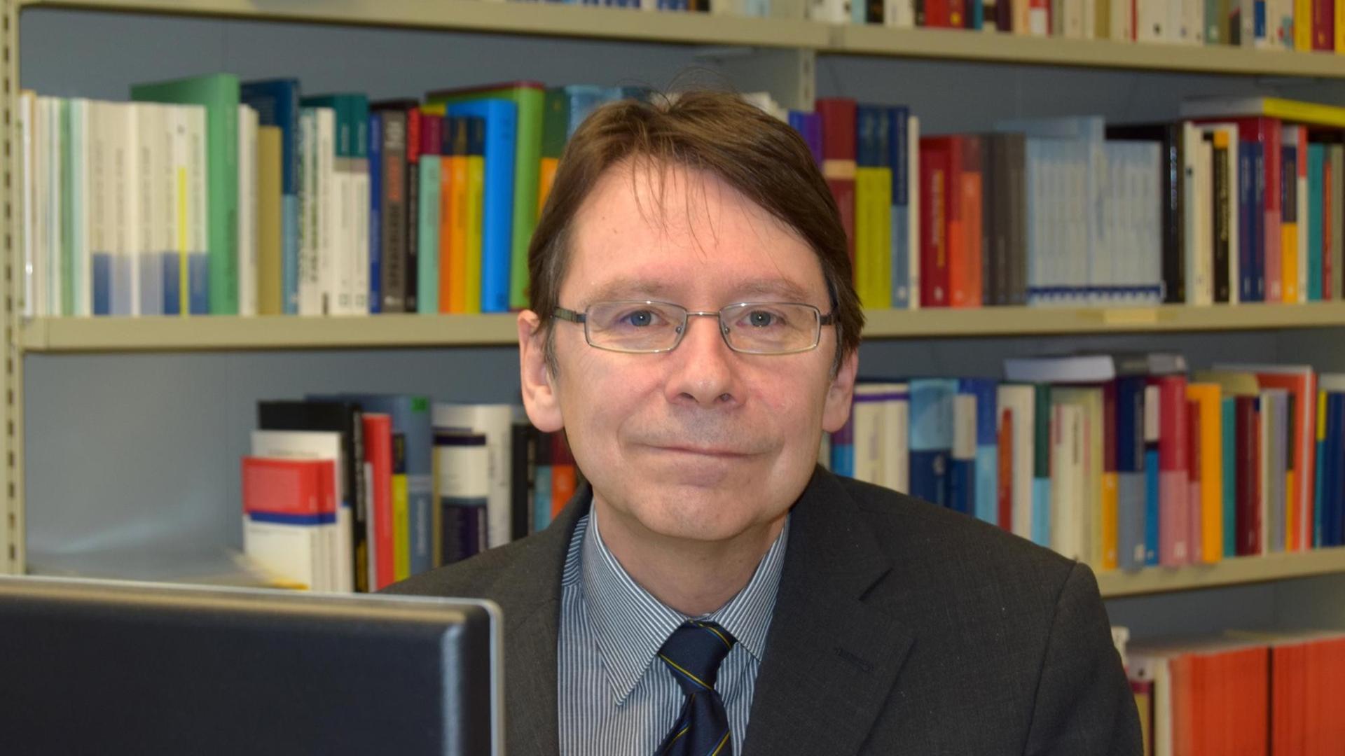 Der Politikwissenschaftler Uwe Jun sitzt in Trier an seinem Schreibtisch in seinem Büro.