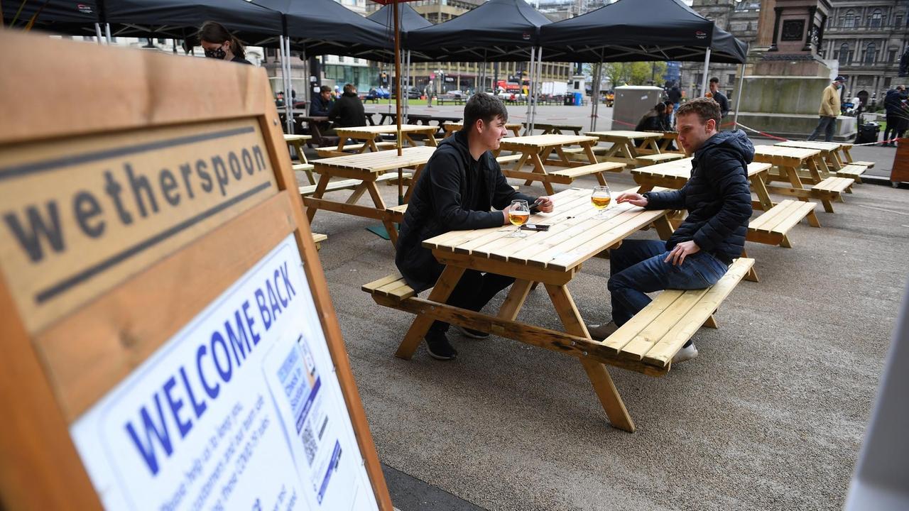Zwei Personen sitzen im Außenbereich eines Pubs in Glasgow. Zwei Personen sitzen im Außenbereich eines Pubs in Glasgow.